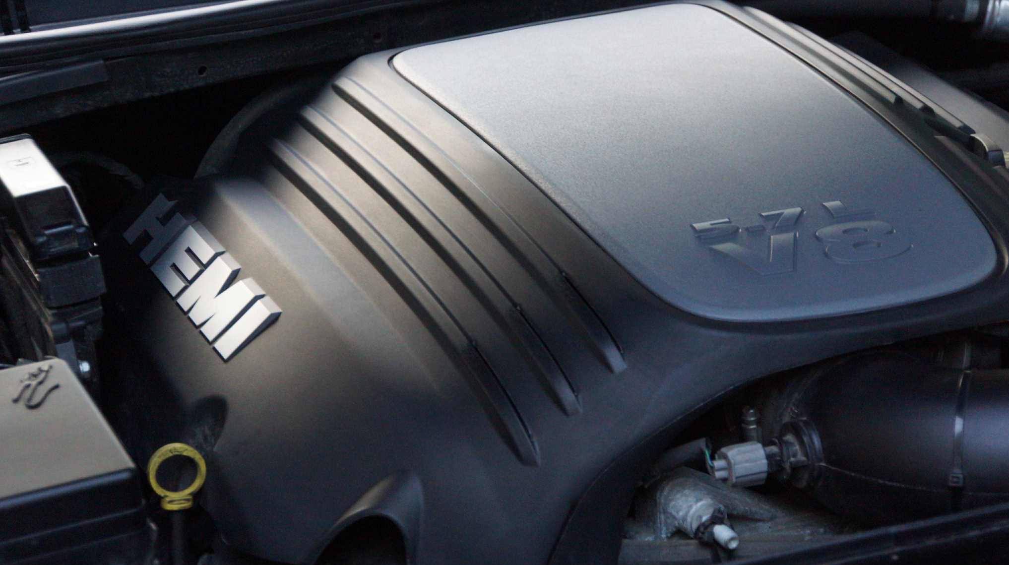 Silnik samochodu z napisem HEMI i oznaczeniem 5.7L V8, widoczne elementy układu dolotowego i pokrywa silnika. Detal w komorze silnikowej.