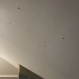 Poddasze po montażu płyt kartonowo-gipsowych, widoczne łączenia płyt i izolacja. Elementy instalacji w tle. Ukończony etap prac wykończeniowych.