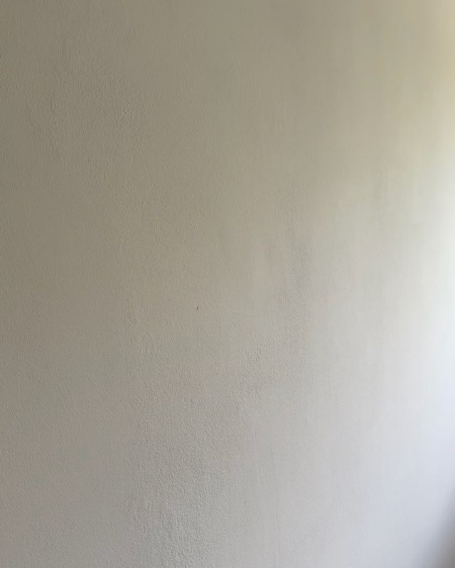Gładka, beżowa ściana po remoncie w mieszkaniu w Warszawie, z delikatną fakturą i subtelnym gradientem światła po prawej stronie.