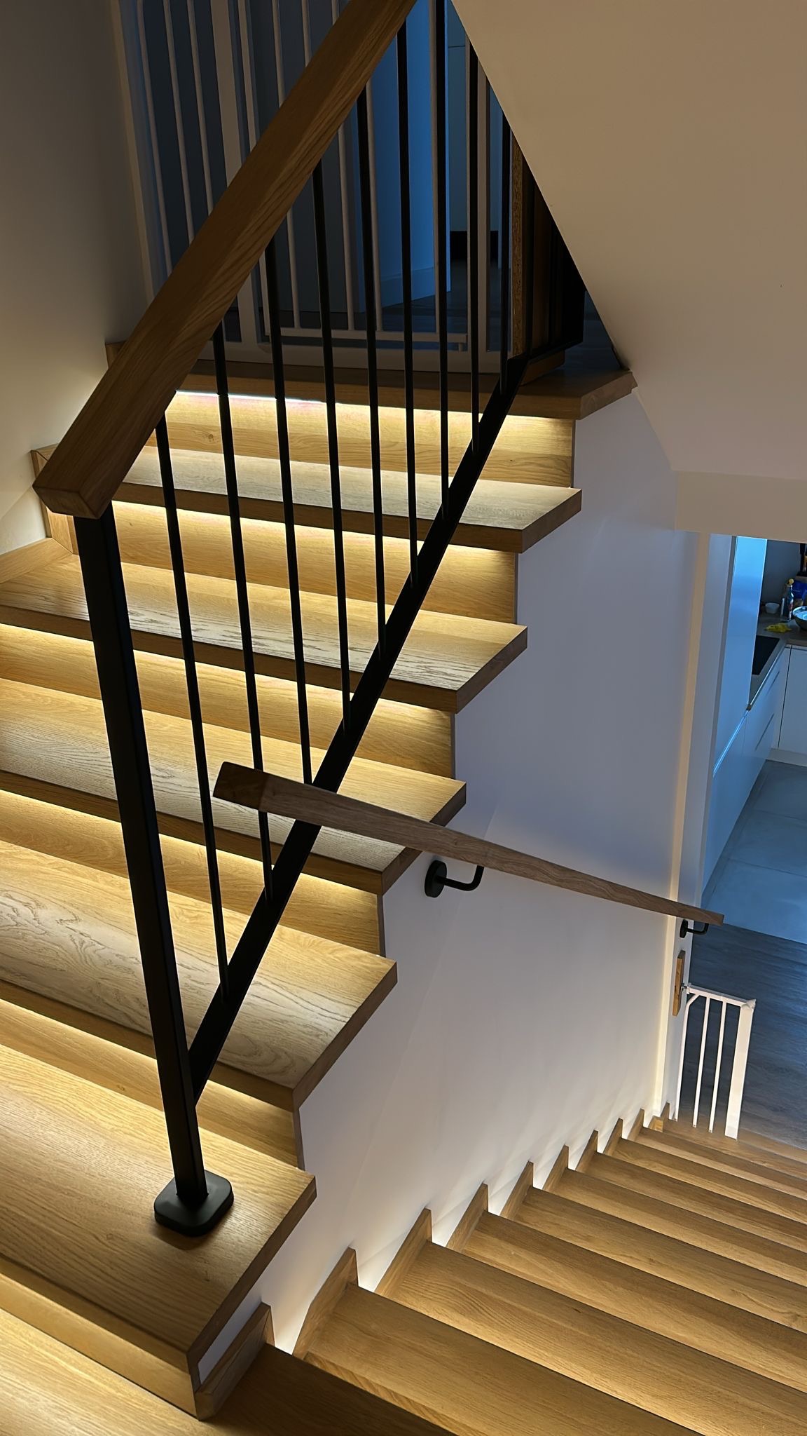 Nowoczesne schody drewniane z czarną balustradą i podświetleniem LED, widok z góry. Minimalistyczny design, jasne drewno, eleganckie wykończenie.