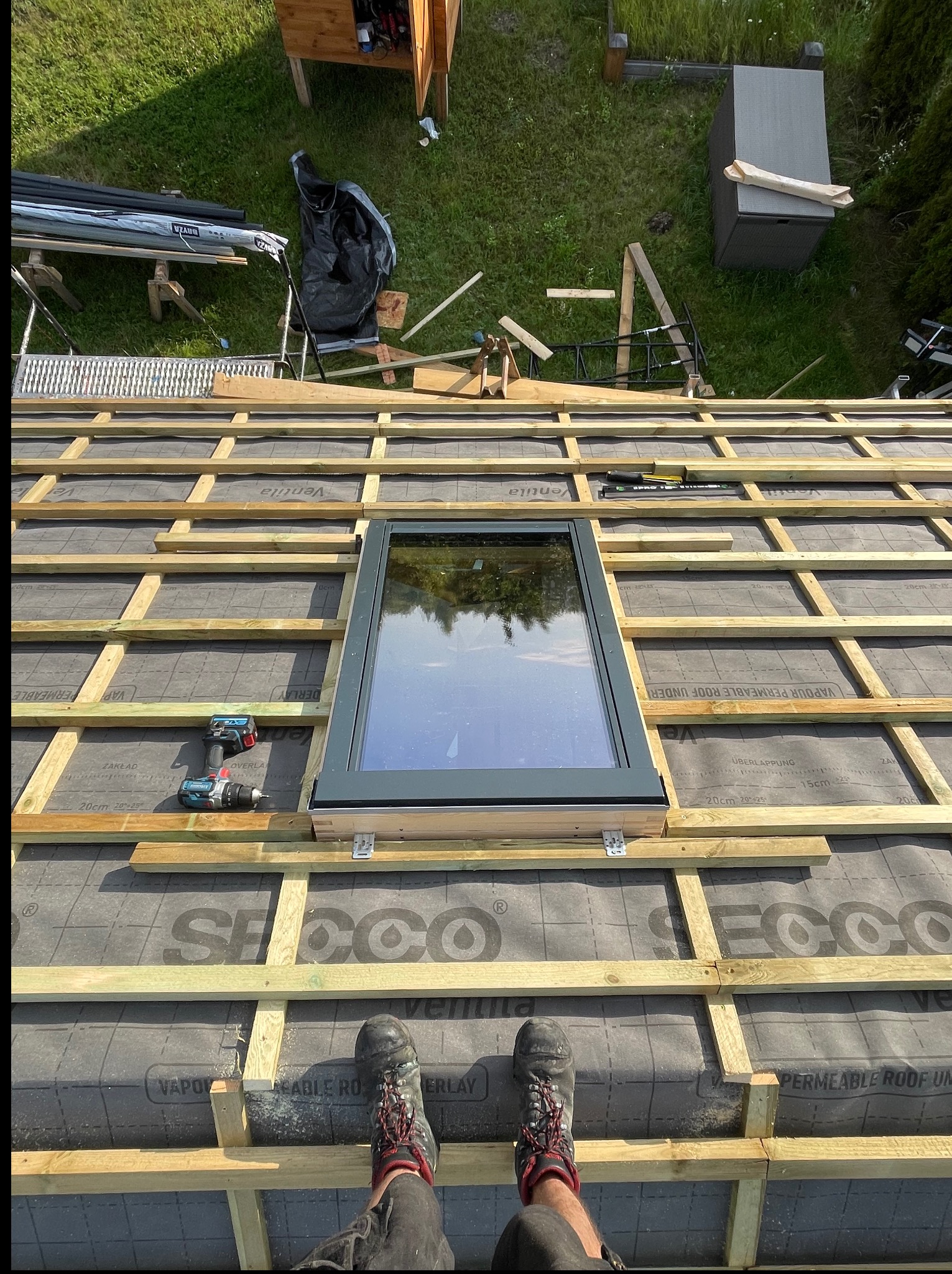 Montaż okna dachowego na drewnianej konstrukcji w Grodzisku Mazowieckim. Widok z góry na ruszt z łat, membranę i narzędzia.