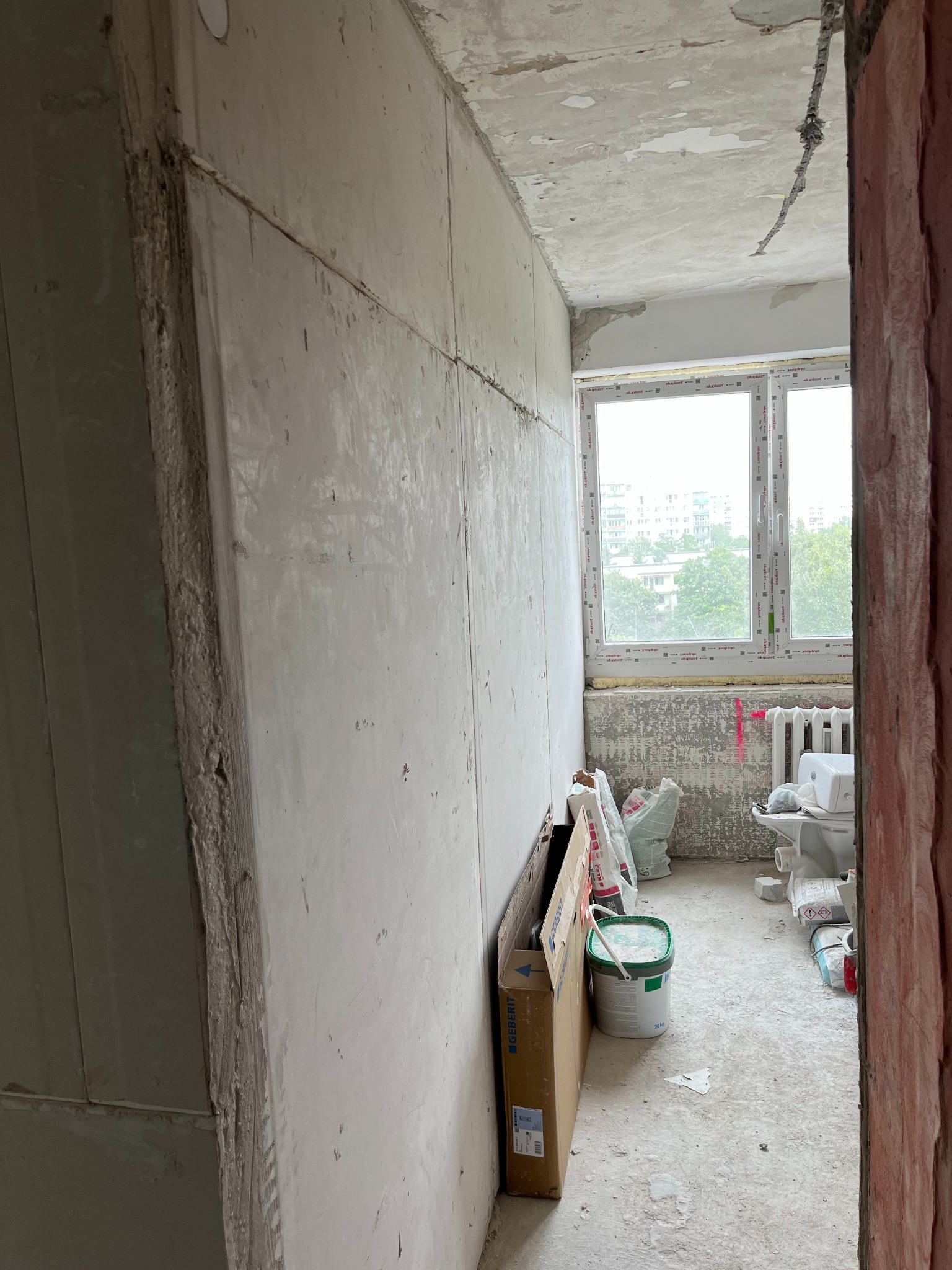 Wnętrze w trakcie remontu w Czosnowie: ściany przygotowane do malowania, widoczne materiały budowlane i instalacja elektryczna pod sufitem.