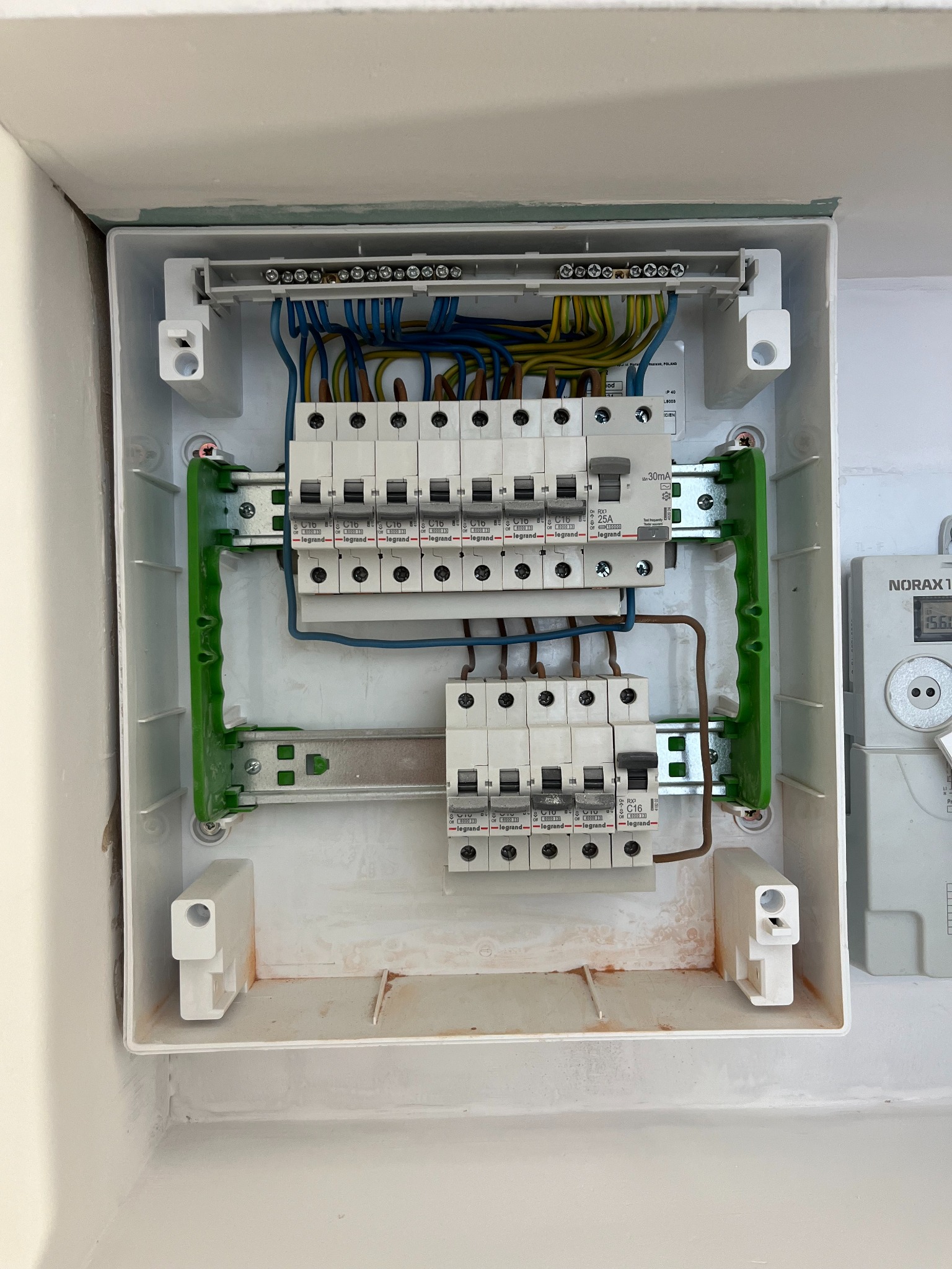 Rozdzielnica elektryczna z bezpiecznikami Legrand, zainstalowana w Czosnowie. Widoczne okablowanie i elementy montażowe. Biała obudowa.