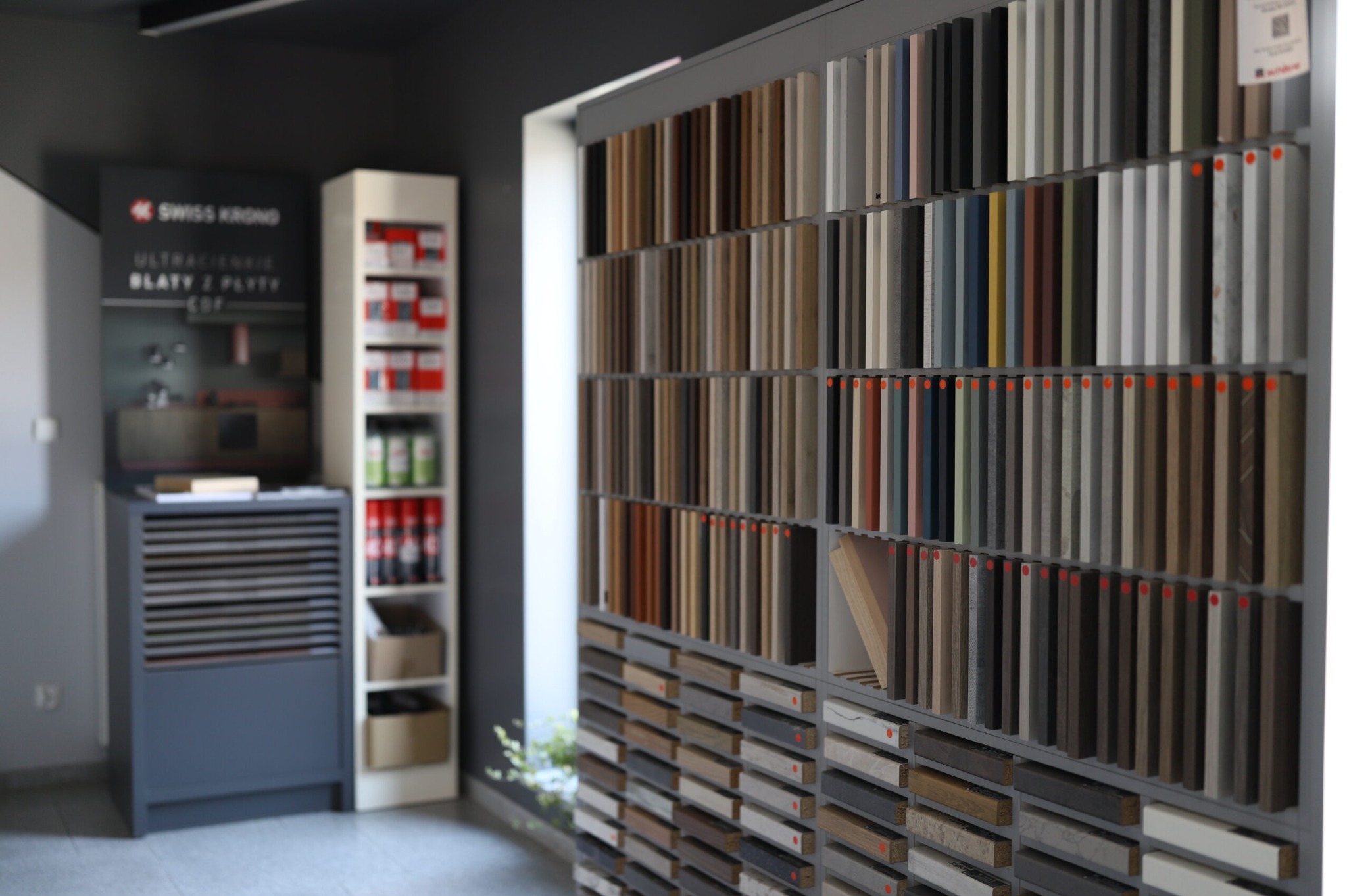 Ekspozycja próbek blatów i płyt meblowych w salonie, prezentująca różnorodność kolorów i faktur materiałów wykończeniowych dla mebli.