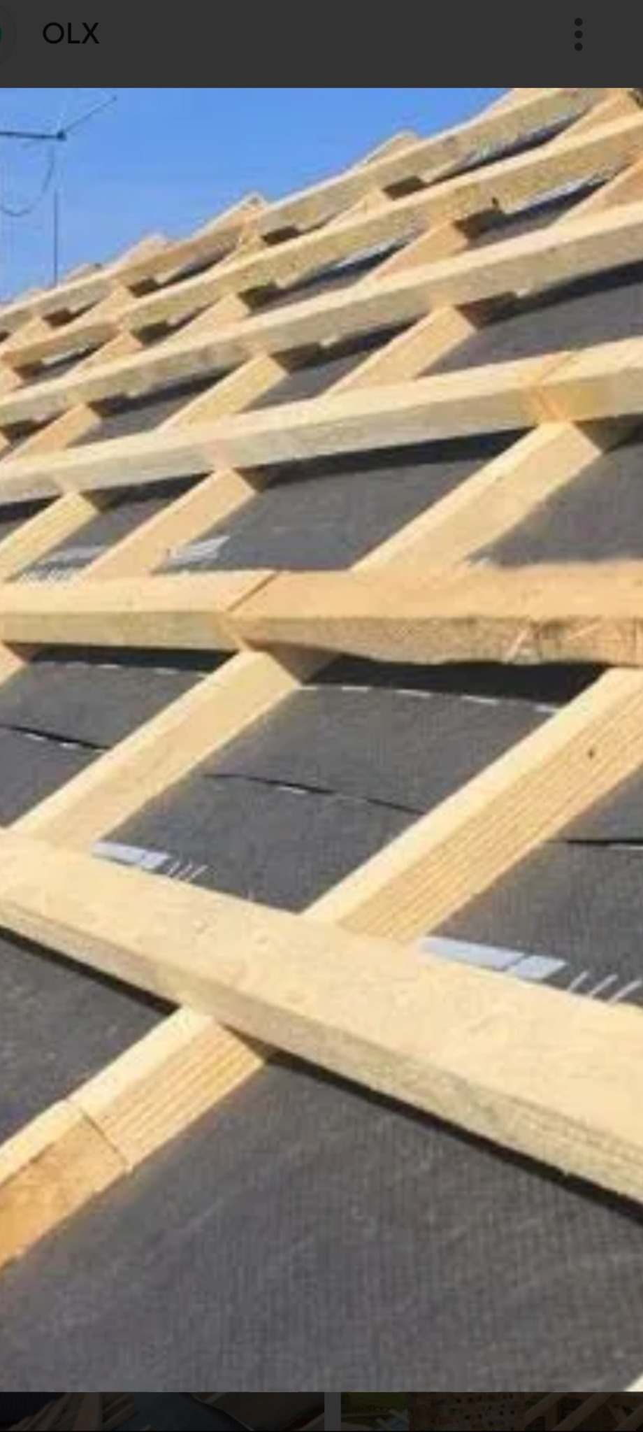 Konstrukcja dachu z drewnianych łat i kontrłat, pokryta czarną membraną dachową, widoczna pod ostrym kątem z dołu do góry, fragment anteny w tle.