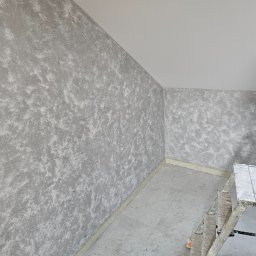 GOODesigne - Pokój po szpachlowaniu z efektem dekoracyjnym na ścianach, widoczna drabina malarska, przygotowane gniazdko elektryczne i listwa przypodłogowa.