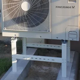 Biała pompa ciepła LG Therma V zamontowana na metalowym stelażu na betonowej podstawie. Widoczny wentylator i logo LG.