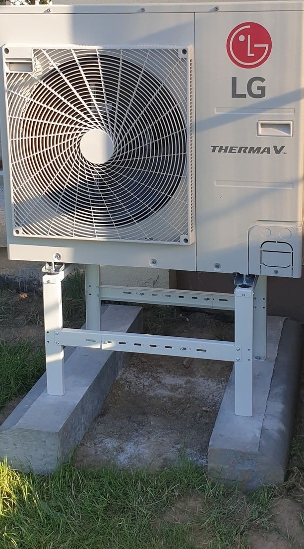 Biała pompa ciepła LG Therma V zamontowana na metalowym stelażu na betonowej podstawie. Widoczny wentylator i logo LG.