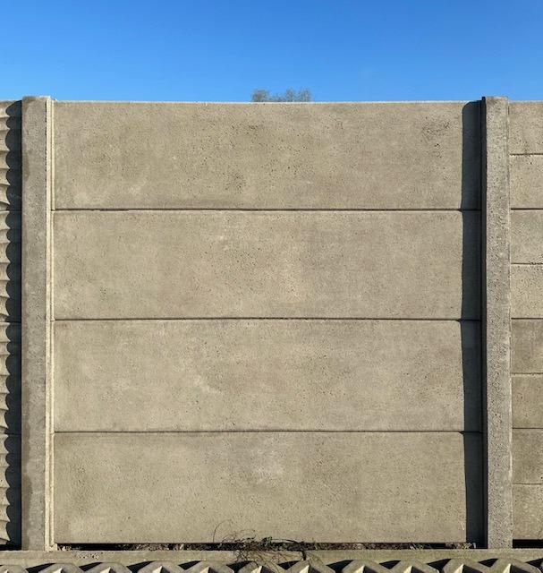 Szczegółowe ujęcie betonowego ogrodzenia modułowego na tle błękitnego nieba, ukazujące fakturę i segmentową konstrukcję paneli.