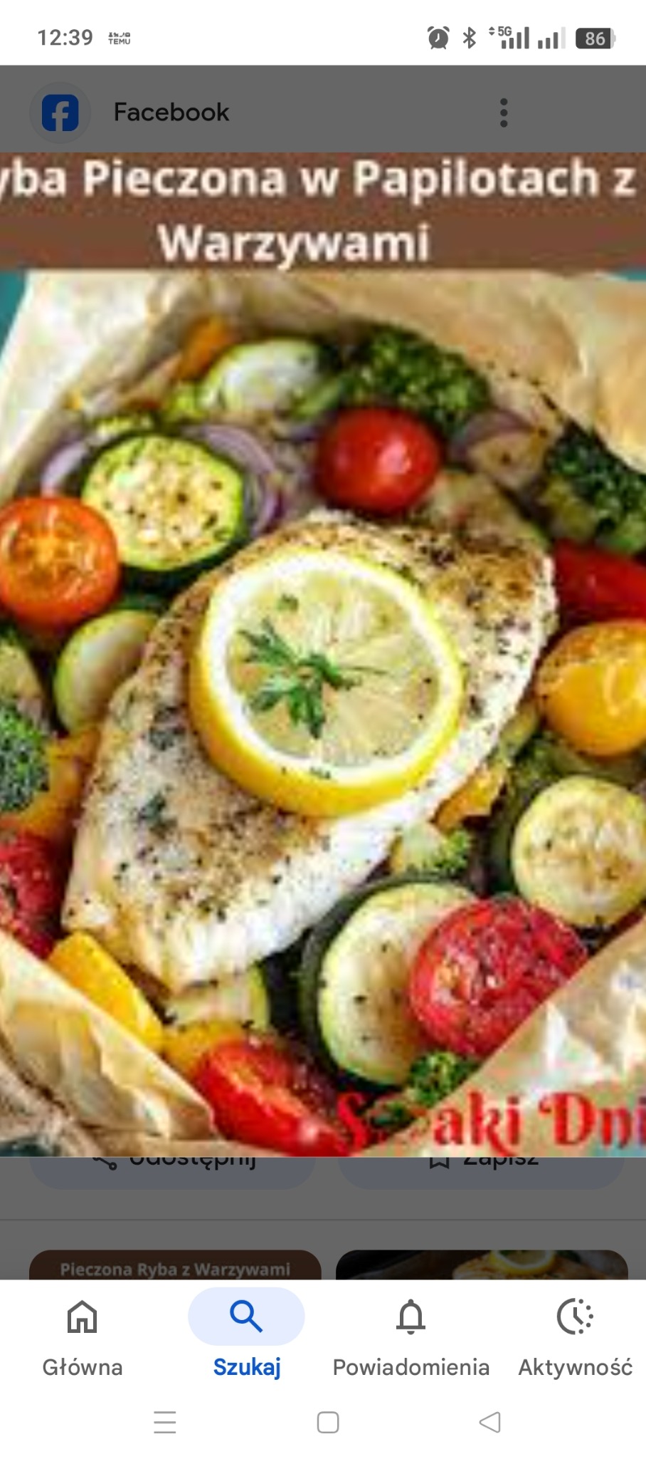 Pieczona ryba z warzywami w papilocie, udekorowana plasterkiem cytryny. Widoczne pomidory, cukinia, brokuły i czerwona cebula. Danie gotowe do spożycia.