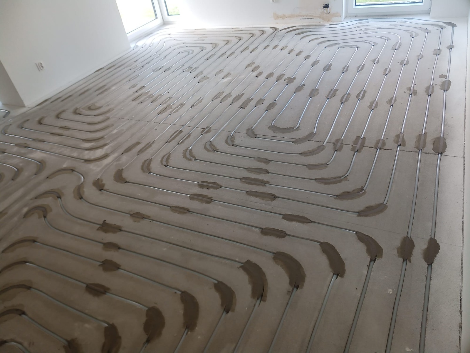 Instalacja ogrzewania podłogowego w trakcie montażu we Wrocławiu. Widoczne rury grzewcze przymocowane do podłoża, przygotowane do zalania wylewką.