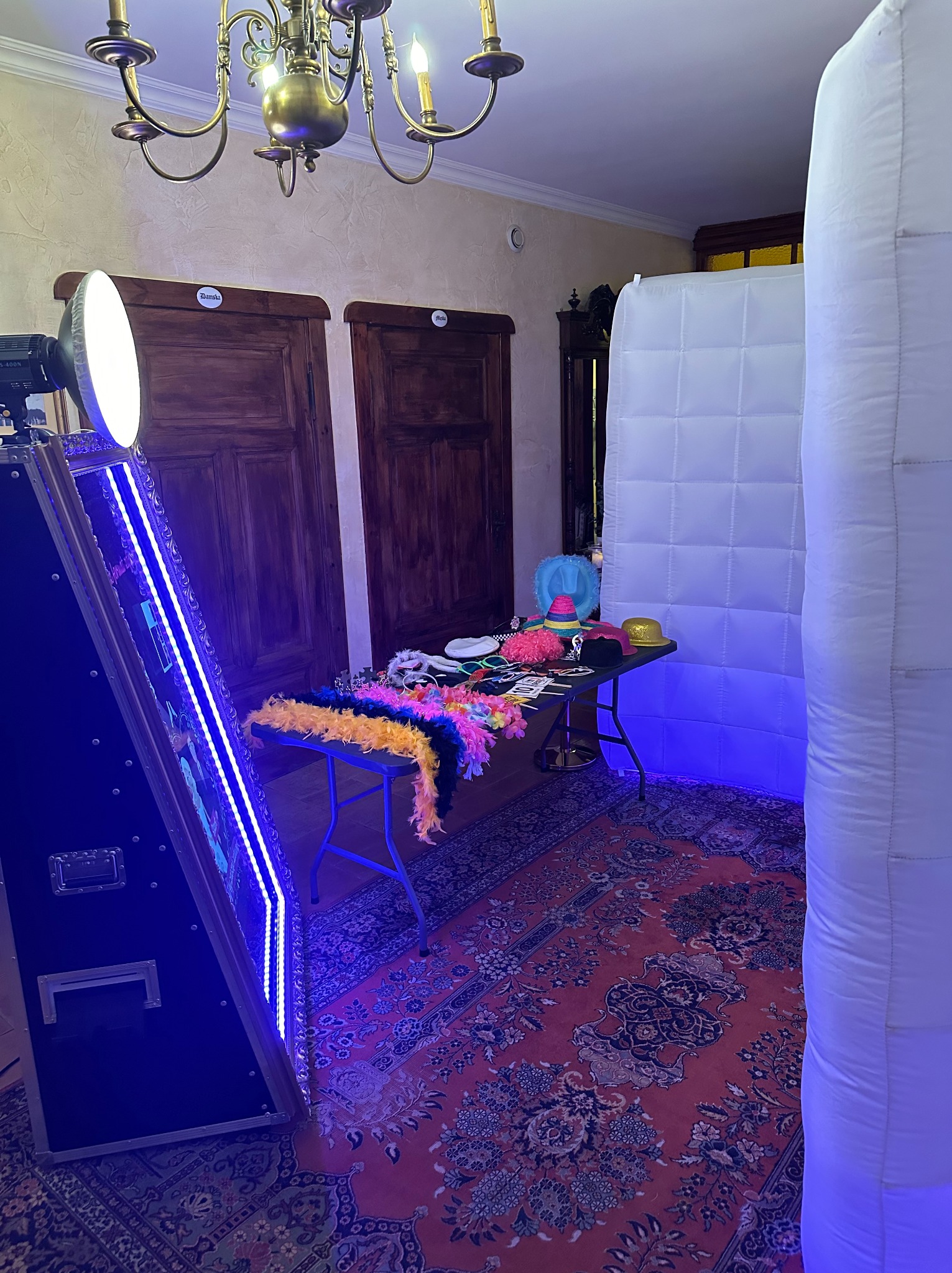 Gotowa do użycia fotobudka z rekwizytami: boa, kapelusze, maski. Biały dmuchany namiot, oświetlenie LED, wzorzysty dywan. Dekoracje na imprezę.