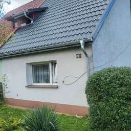 Termo - Tech Termomodernizacja Kamil Żurawowicz - Dom z nowym, ciemnoszarym dachem z blachodachówki trapezowej i orynnowaniem. Widoczna elewacja budynku z numerem 13/1.