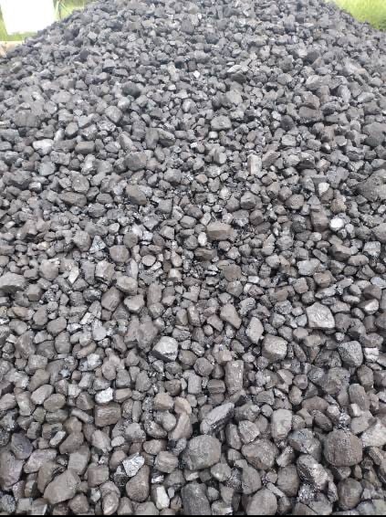 Góra antracytu o różnej wielkości bryłach, z widocznymi krawędziami i fakturą, oświetlona naturalnym światłem, na zewnątrz.