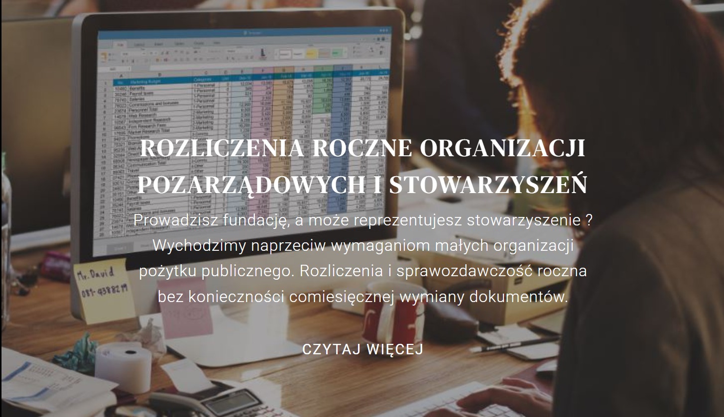 Rozliczenia roczne organizacji pozarządowych prezentowane na ekranie komputera, kalkulator, notatki na biurku, osoba pisząca na klawiaturze.