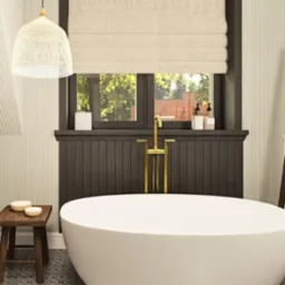 Elegancka łazienka z wolnostojącą wanną na tle okna z roletą rzymską. Drewniany taboret i złota armatura dodają wnętrzu ciepła i luksusu.