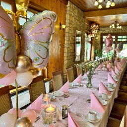 BALONOLA Aleksandra Daros - Dekoracja stołu na imprezę w Czempiniu: różowe serwetki, balony w kształcie motyli, świece w szklanych naczyniach, kwiaty, zastawa stołowa w rustykalnym wnętrzu.