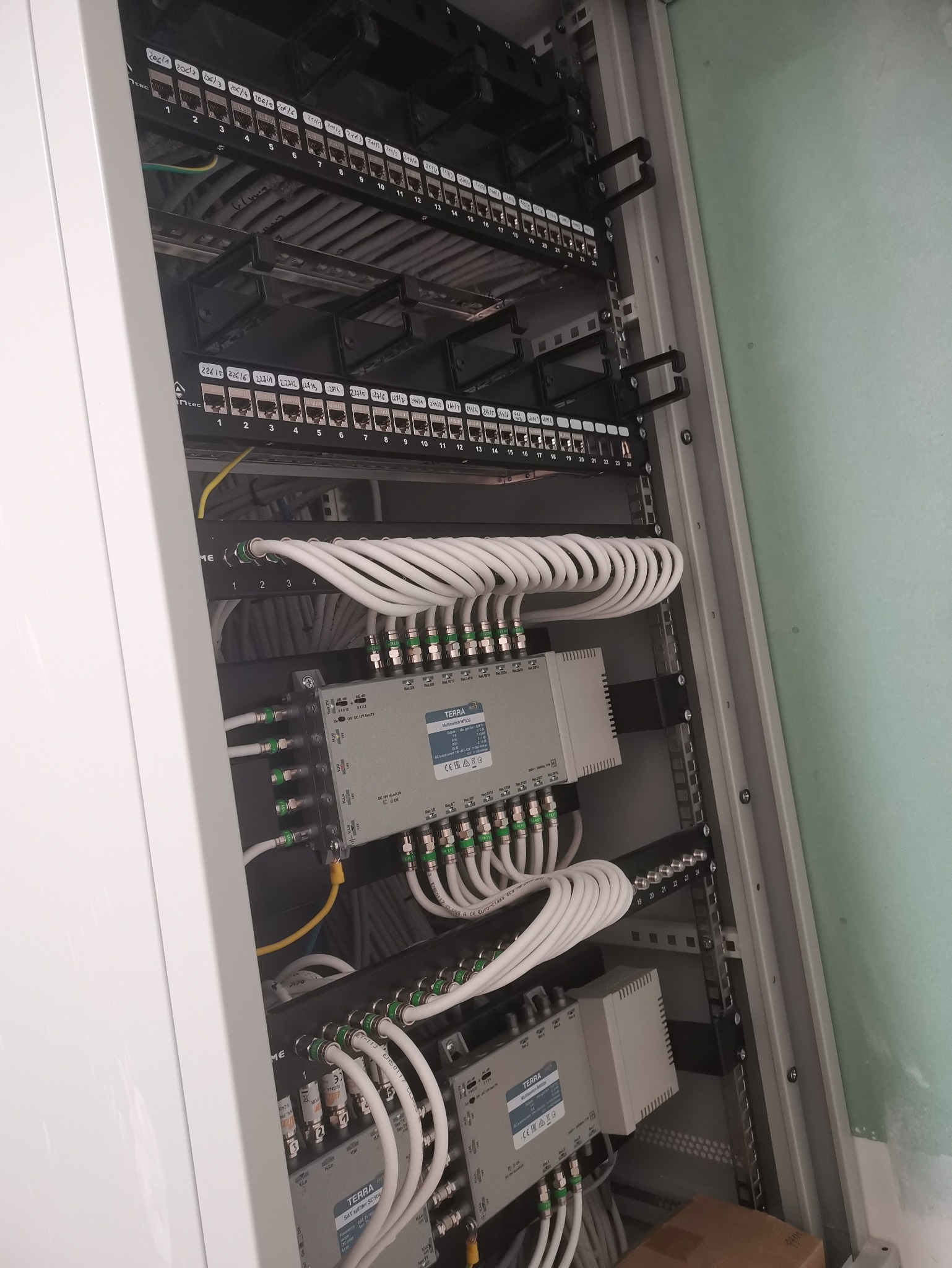Szafa telekomunikacyjna z patch panelem, kablami koncentrycznymi i multiswitchem TERRA MR532. Instalacja kablowa wewnątrz szafy rack, widok od frontu.
