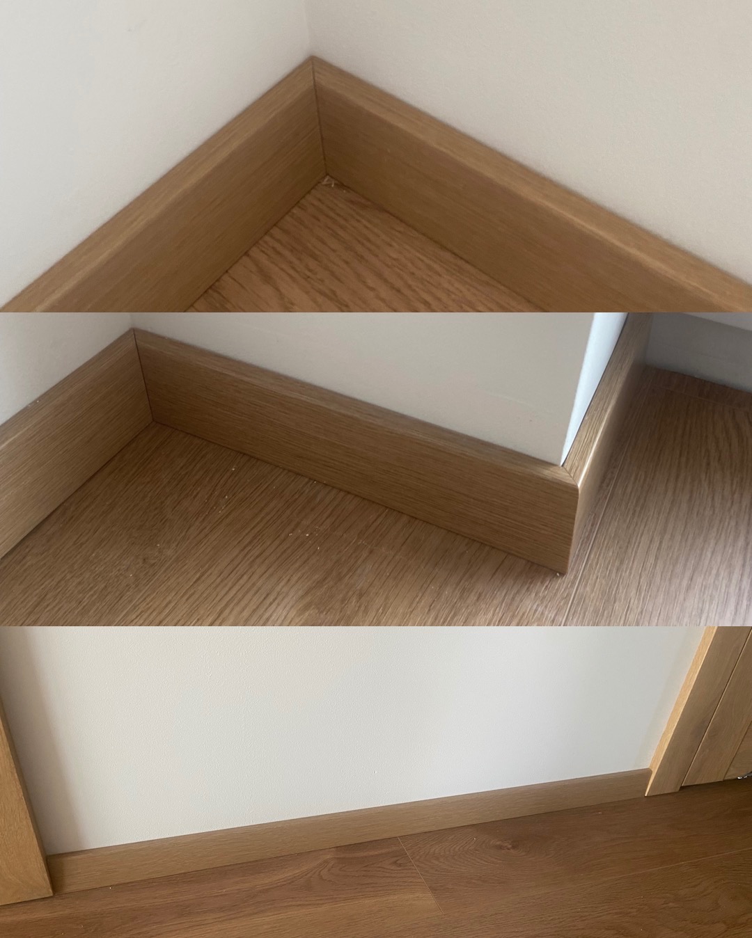 Zamontowane, drewnopodobne listwy przypodłogowe w rogu pomieszczenia, z widoczną strukturą drewna i drobnymi zabrudzeniami na podłodze. Białe ściany, ciepłe oświetlenie.