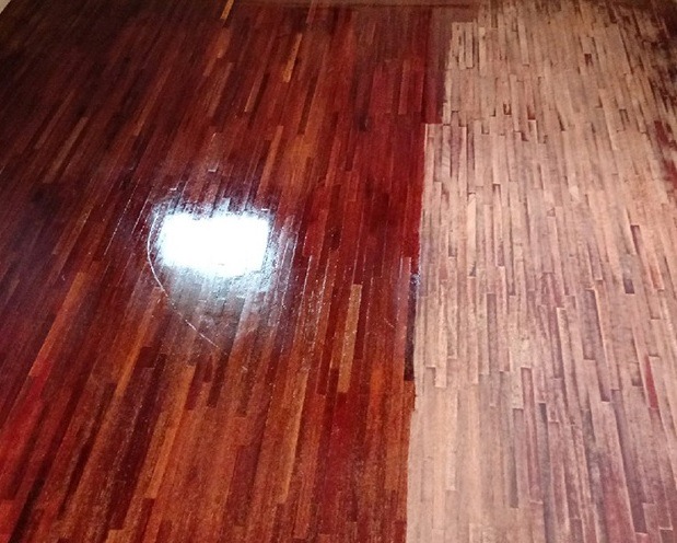 Parkiet po cyklinowaniu: połowa odnowiona, druga surowa, ukazująca różnicę przed i po zabiegu. Widoczne naturalne drewno i połysk lakieru.