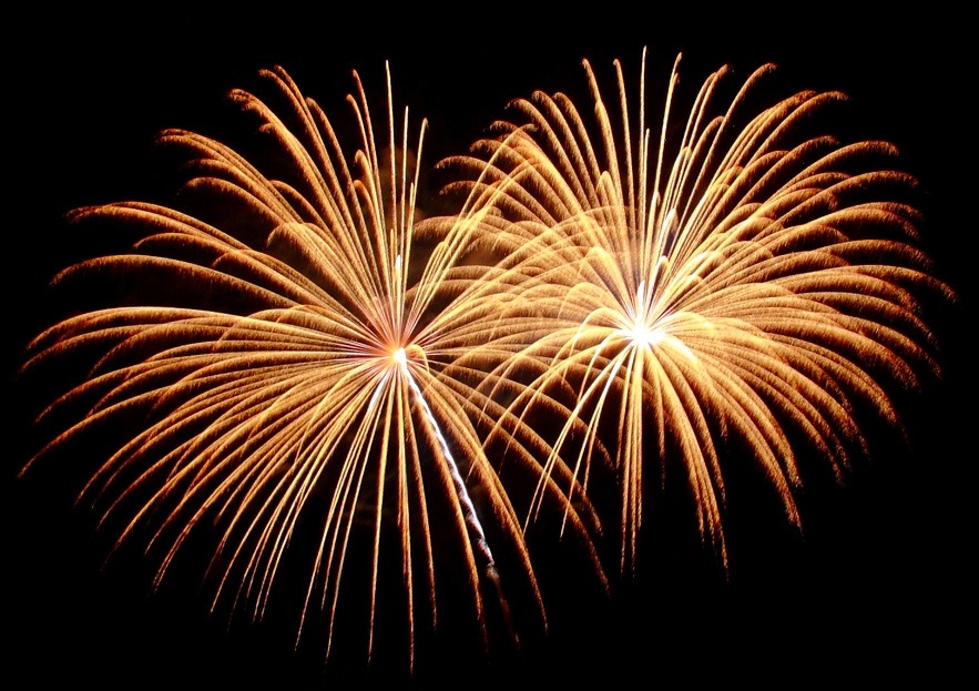 Dwa złote, rozświetlone fajerwerki na czarnym tle, ukazane w pełnej krasie. Szczegółowe ujęcie eksplozji, idealne na imprezy i uroczystości.
