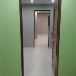 OFERTEO S.A - Pomalowane na jasno ściany mieszkania po remoncie, widok z korytarza przez otwarte drzwi do kolejnych pomieszczeń. Świeże, pastelowe kolory.