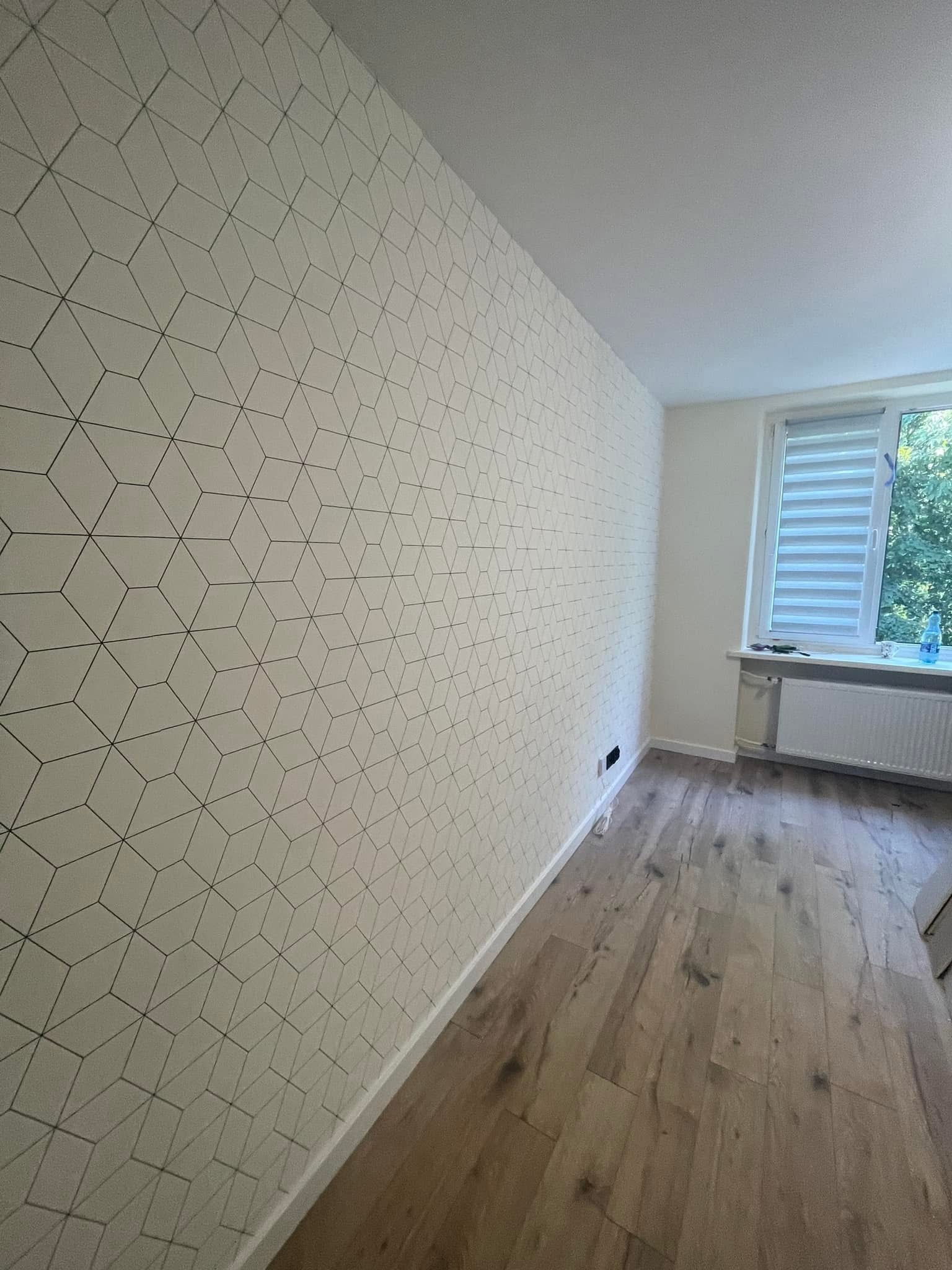 Pokój po remoncie: geometryczna tapeta na ścianie, drewniana podłoga, okno z żaluzjami. Jasne wnętrze z nowoczesnym designem.