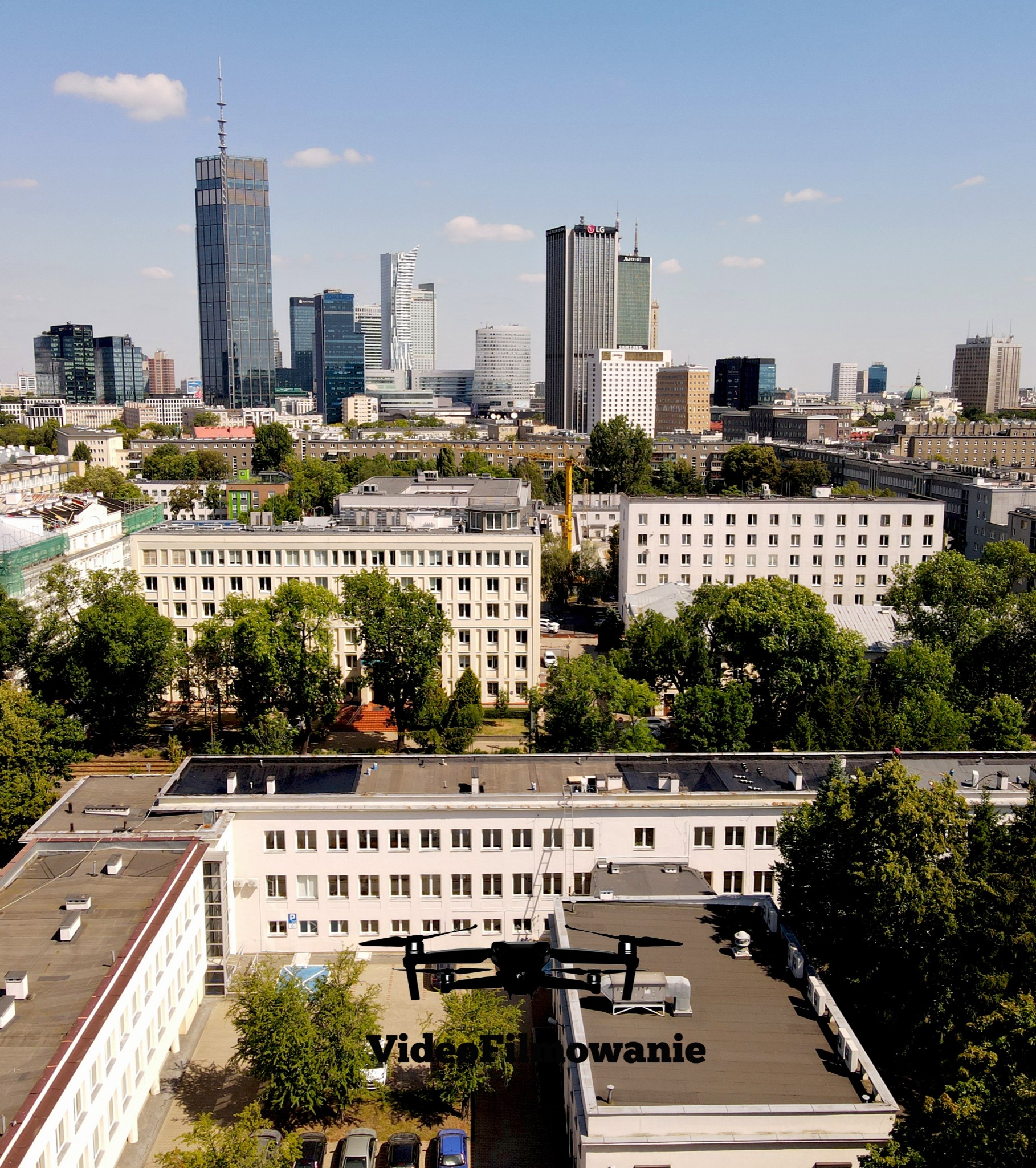 Warszawa z lotu drona, widok na budynki i panoramę miasta w słoneczny dzień. Dron w locie nad dachem budynku. Napis 'Video Filmowanie' na dachu.