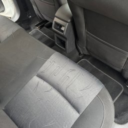 VILUX Jakub Gil - Szczegółowe ujęcie tylnej, czarno-szarej tapicerki samochodowej z widocznymi zapięciami ISOFIX i wzorem na siedzeniu. Widoczny fragment podłogi i konsoli.