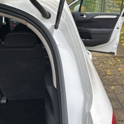 VILUX Jakub Gil - Otwarty bagażnik białego samochodu z widocznym wnętrzem i elementami karoserii, drzwi pojazdu otwarte na tle jesiennych drzew.