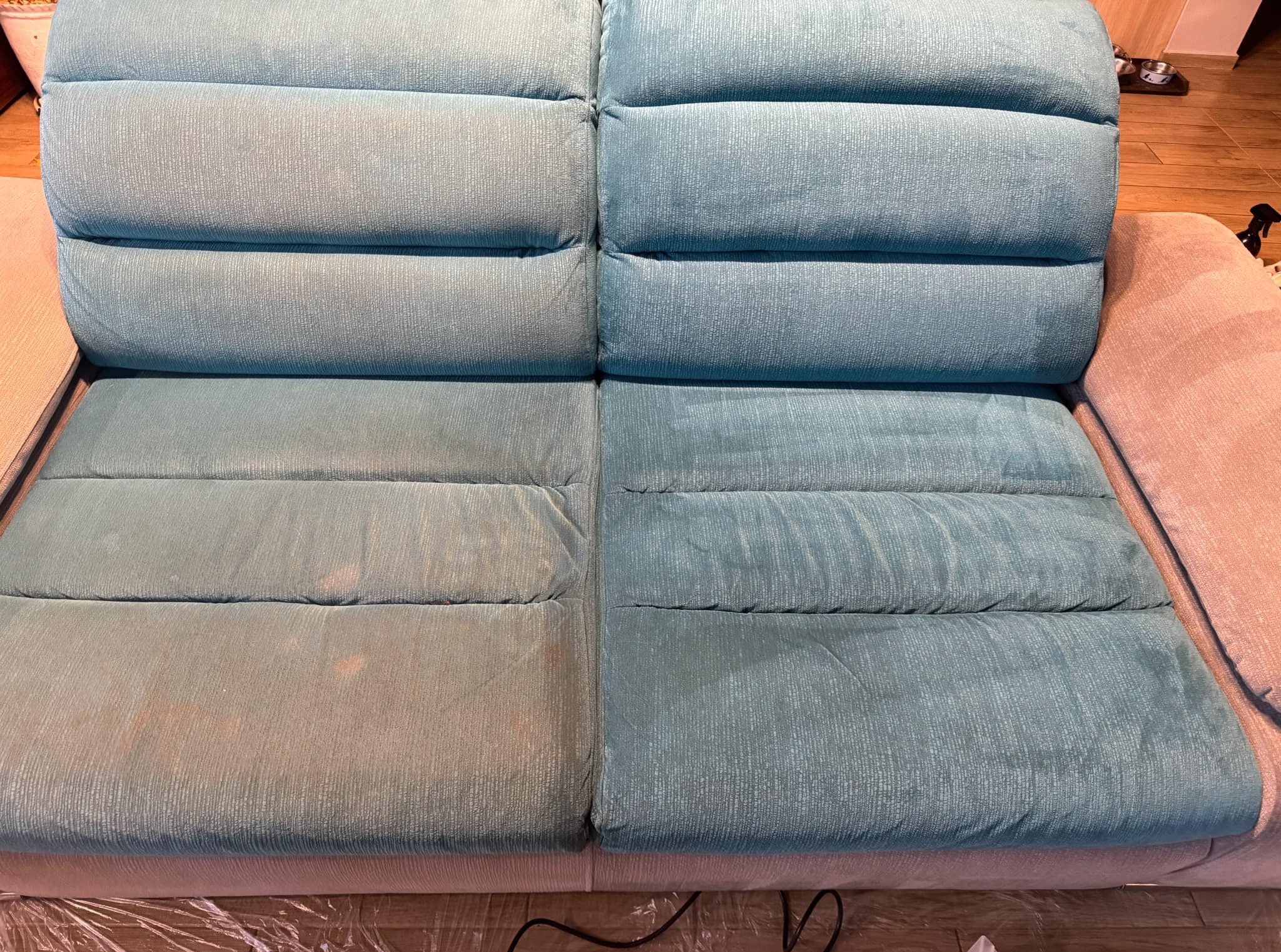 Sofa z wyraźnym podziałem na część wyczyszczoną i zabrudzoną, ukazująca efekt prania tapicerki. Widoczne różnice w kolorze i strukturze materiału.