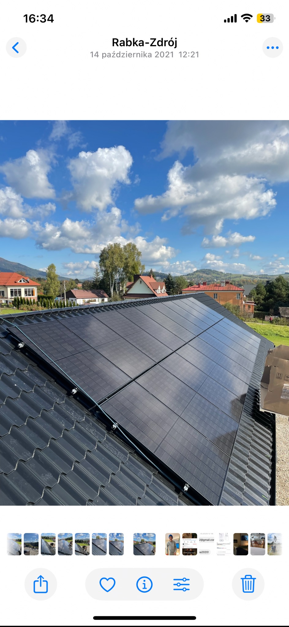 Panele fotowoltaiczne na dachu domu w Rabce-Zdroju, widok z góry, błękitne niebo z chmurami w tle. Częściowo widoczne kartony po panelach.