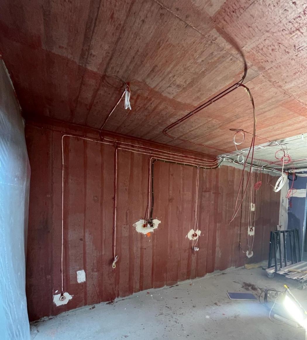 Instalacja elektryczna w surowym wnętrzu w Ostrowcu Świętokrzyskim: przewody poprowadzone po ścianach i suficie, przygotowane punkty pod gniazdka i oświetlenie.