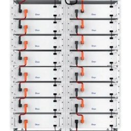Master Investment Sp. z o.o. - Rząd białych akumulatorów z pomarańczowymi złączami i czarnymi kablami, tworzących system magazynowania energii. Widoczny panel sterowania na górze.