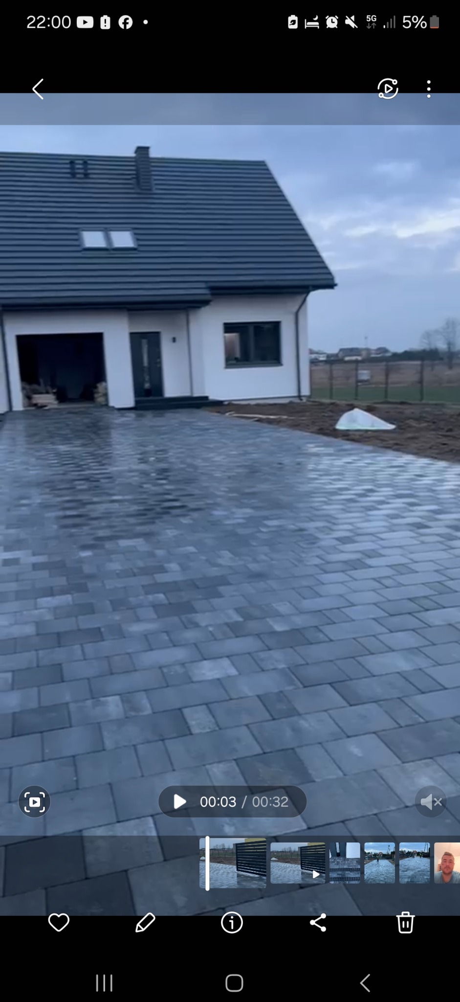 Nowoczesny podjazd z szarej kostki brukowej prowadzący do domu w Łodzi. Widoczne świeżo ułożone kostki i fragment ogrodu.