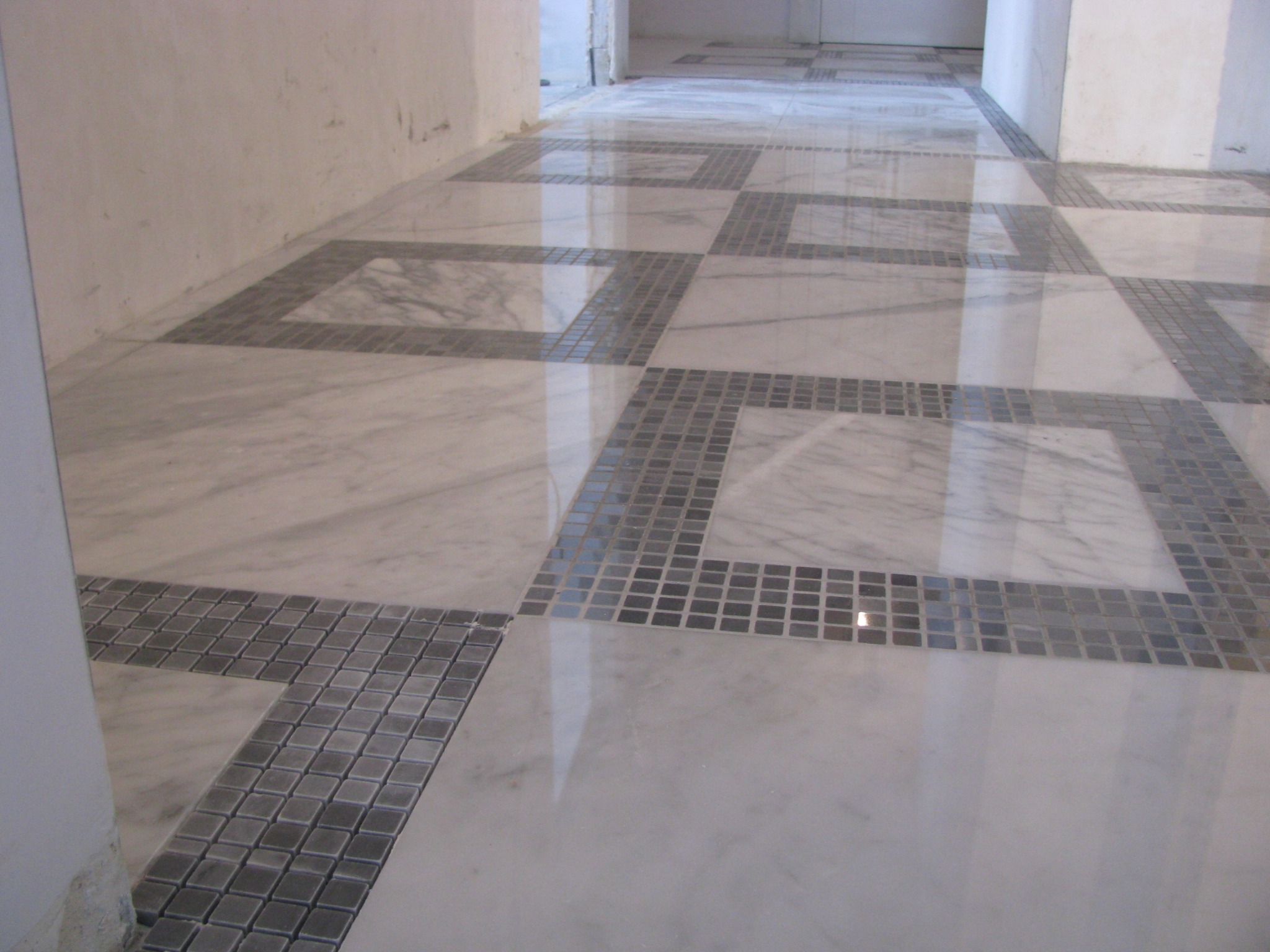 Błyszcząca podłoga z białego marmuru z szarymi, kwadratowymi mozaikami tworzącymi geometryczny wzór. Widok z perspektywy podłogi, surowe ściany w tle.