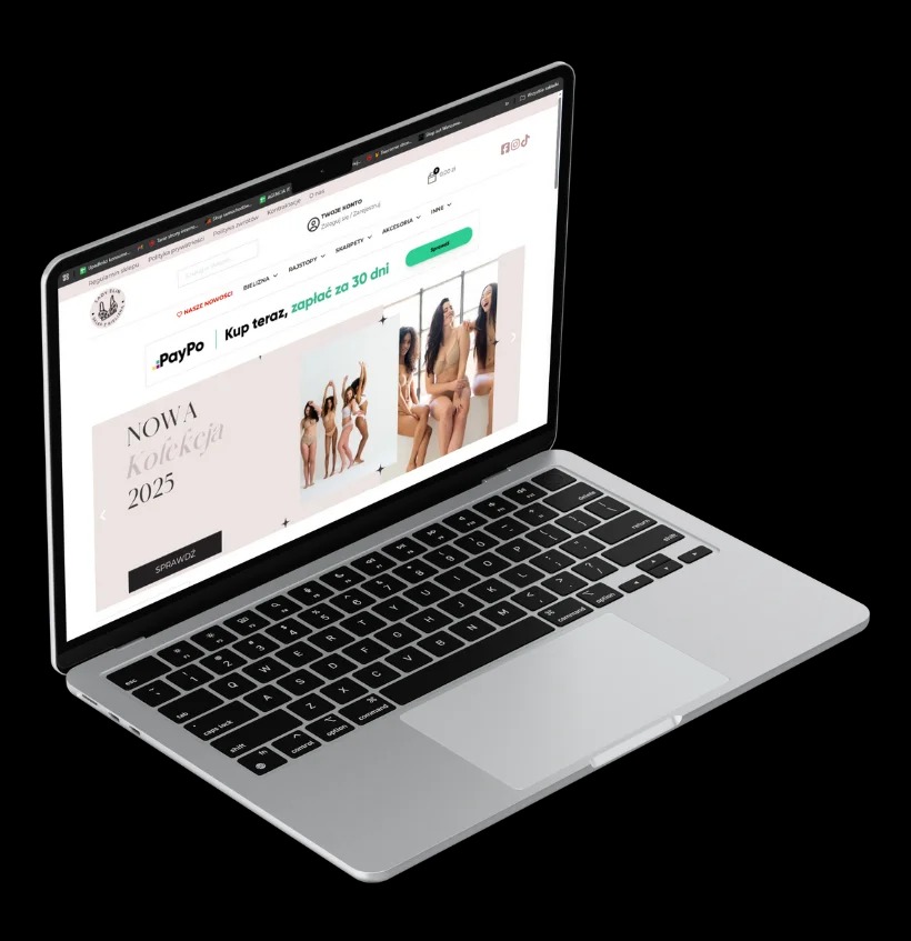 Ekran laptopa wyświetla stronę sklepu internetowego z nową kolekcją bielizny na rok 2025. Widoczny panel logowania, menu i slider z modelkami. Laptop na czarnym tle.