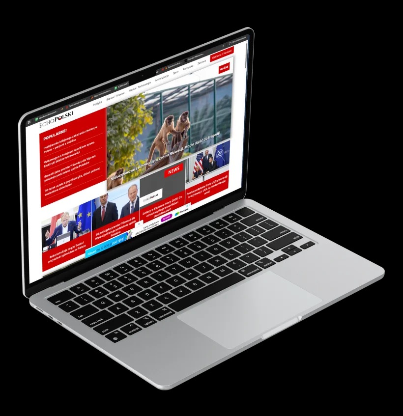 Laptop prezentuje stronę internetową z artykułami informacyjnymi, wyróżniającą się układem graficznym i czytelną typografią na jasnym tle.