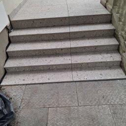 Stone MCh - Wykończone schody zewnętrzne z płytek imitujących kamień, prowadzące na taras. Widoczne detale wykończenia i faktura materiału.