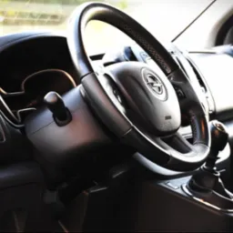 Wnętrze samochodu Opel: kierownica z logo, deska rozdzielcza i dźwignia zmiany biegów. Nowoczesny design kabiny pojazdu do przewozu osób.