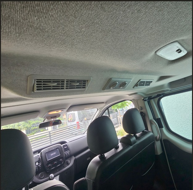 Wnętrze busa z widocznymi fotelami, klimatyzacją sufitową i deską rozdzielczą. Widok z tylnych siedzeń, wnętrze czyste i zadbane, gotowe do bezpiecznego transportu.