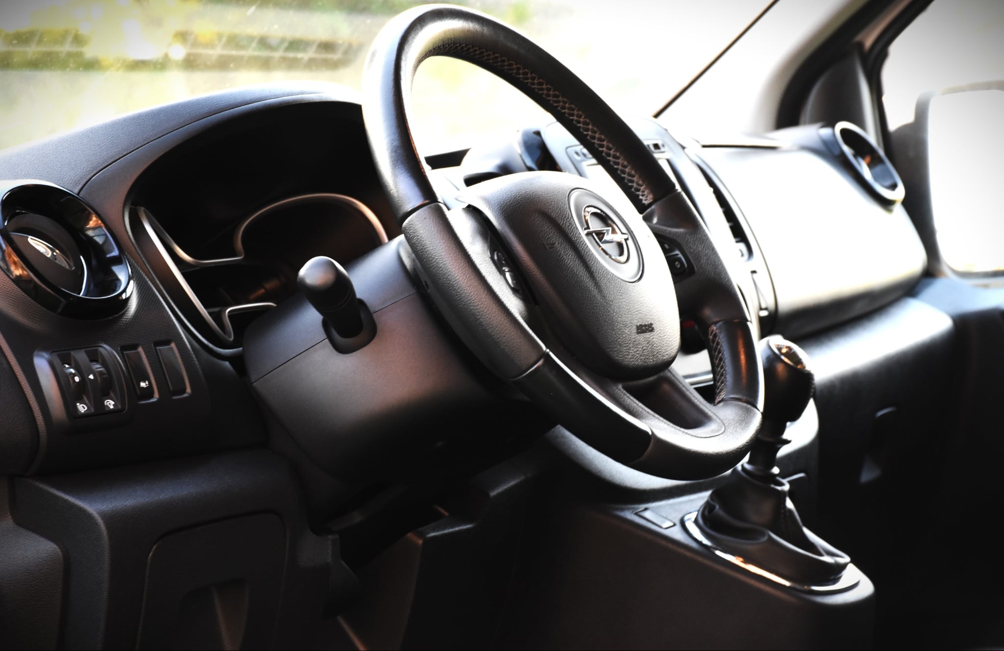 Wnętrze samochodu Opel: kierownica z logo, deska rozdzielcza i dźwignia zmiany biegów. Nowoczesny design kabiny pojazdu do przewozu osób.