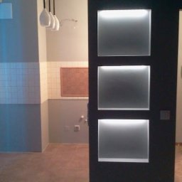 USŁUGI BUDOWLANE DARIUSZ RADOMSKI - Nowoczesna łazienka z oświetleniem LED w ścianie i wiszącymi lampami. Widoczne płytki i obraz na ścianie. Minimalistyczny design.