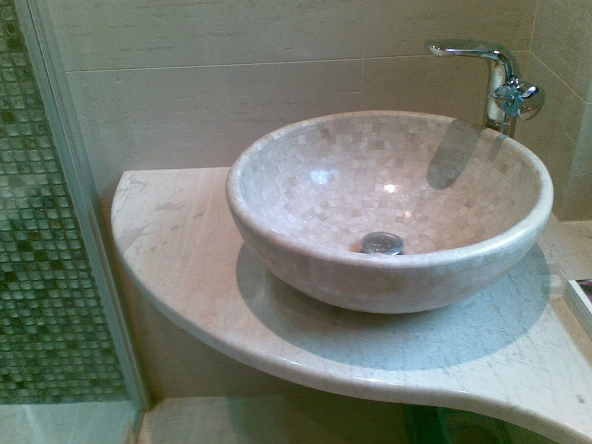 Beżowa, mozaikowa umywalka nablatowa z chromowaną baterią, osadzona na marmurowym blacie w łazience z kabiną prysznicową wykończoną mozaiką.