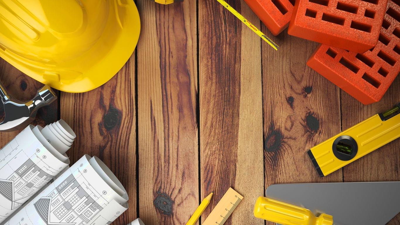 Plan budowlany, kask, cegły i narzędzia na drewnianym tle. Perspektywa z góry, neutralne oświetlenie.