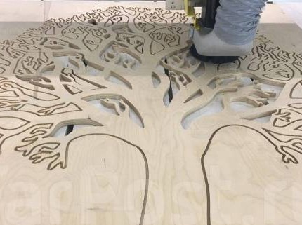 Precyzyjne wycinanie wzoru drzewa w sklejce za pomocą frezarki CNC. Jasne drewno, widoczne detale wycinanego motywu.