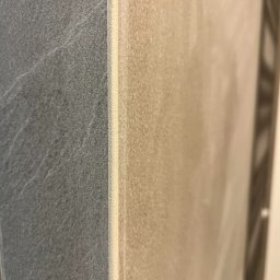 InnerLine Oleh Khomyn - Szczegółowe zbliżenie na połączenie płytek w łazience: szara płytka imitująca kamień sąsiaduje z beżową, z widoczną fugą.