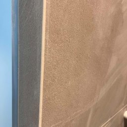 InnerLine Oleh Khomyn - Detal wykończenia ściany z beżowych płytek, widoczny narożnik i fuga. Minimalistyczny design, neutralna kolorystyka, ciepłe oświetlenie.