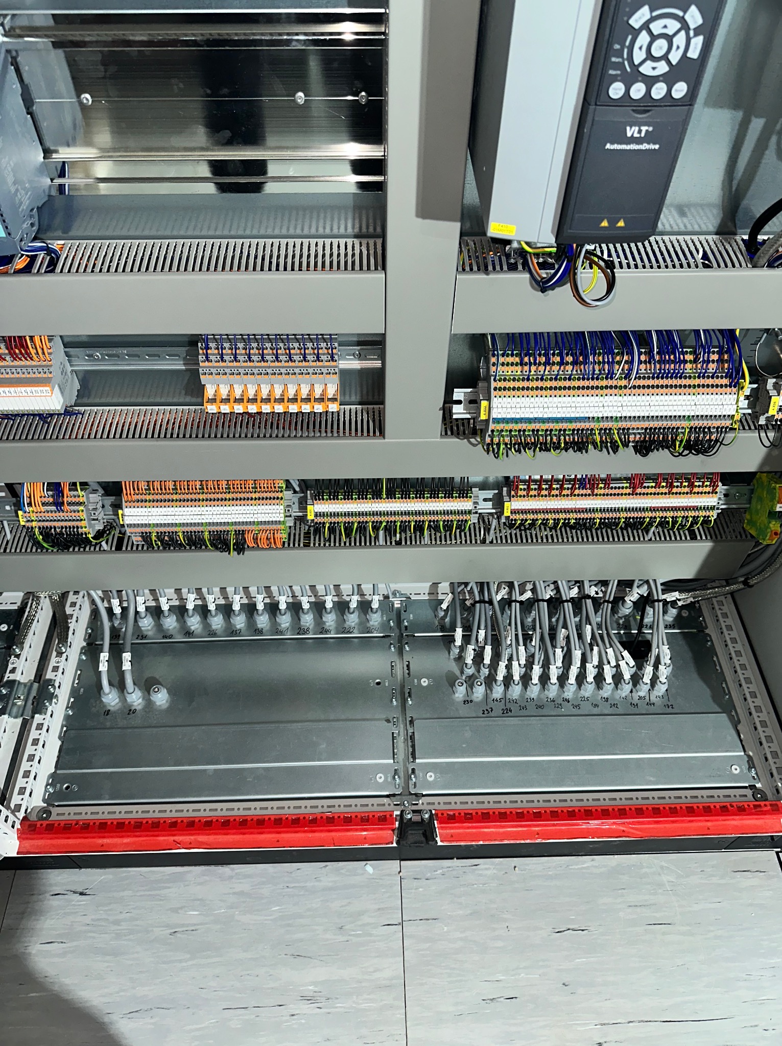 Szczegółowe ujęcie rozdzielnicy elektrycznej z licznymi przewodami, złączkami i sterownikiem VLT AutomationDrive wewnątrz metalowej szafy.