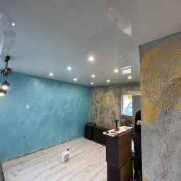 Fach-Mal - Wykończone wnętrze w Chodzieży: błękitna ściana z efektem ombre, sufit napinany z oświetleniem punktowym, dekoracyjna ściana z motywem ornamentu i sprzęt do pracy.